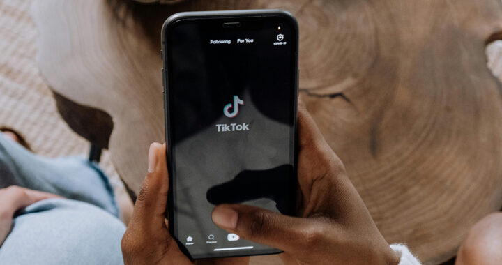 Hände die ein Handy halten, auf dem das Logo von TikTok zu sehen ist.