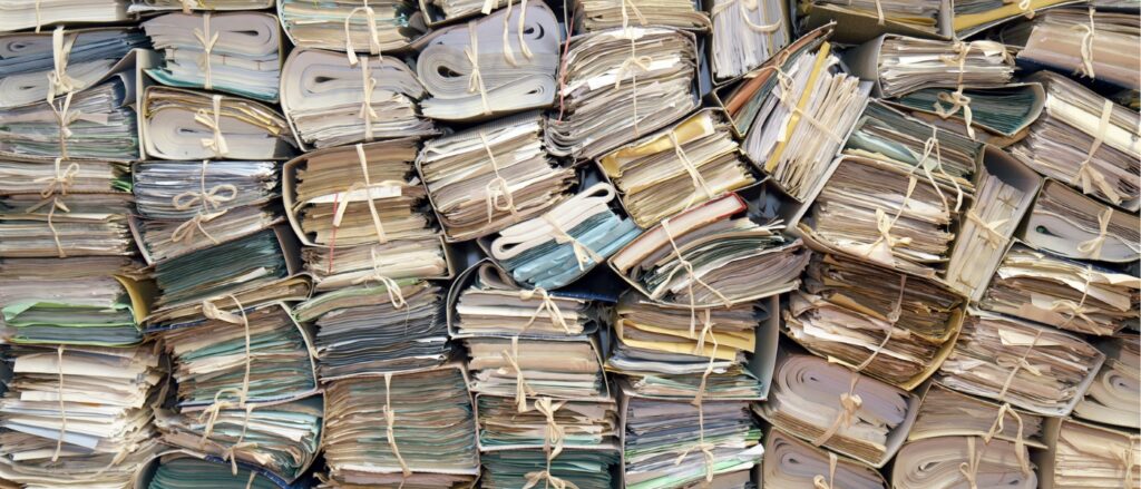 Zahlreiche gestapelte Papierakten in einem Archiv