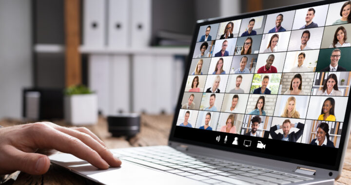 Laptop, auf dem ein Videokonferenzbildschirm mit vielen kleinen Teilnehmerkacheln angezeigt wird.