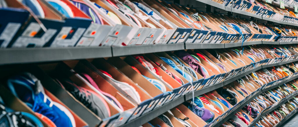 Regale mit zahlreichen Sneakern in offenen Kartons, dicht aneinandergereiht in einem Geschäft.