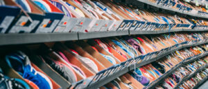 Regale mit zahlreichen Sneakern in offenen Kartons, dicht aneinandergereiht in einem Geschäft.