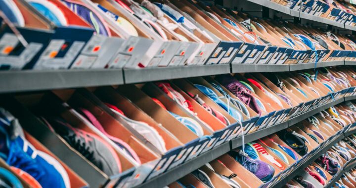 Regale mit zahlreichen Sneakern in offenen Kartons, dicht aneinandergereiht in einem Geschäft.