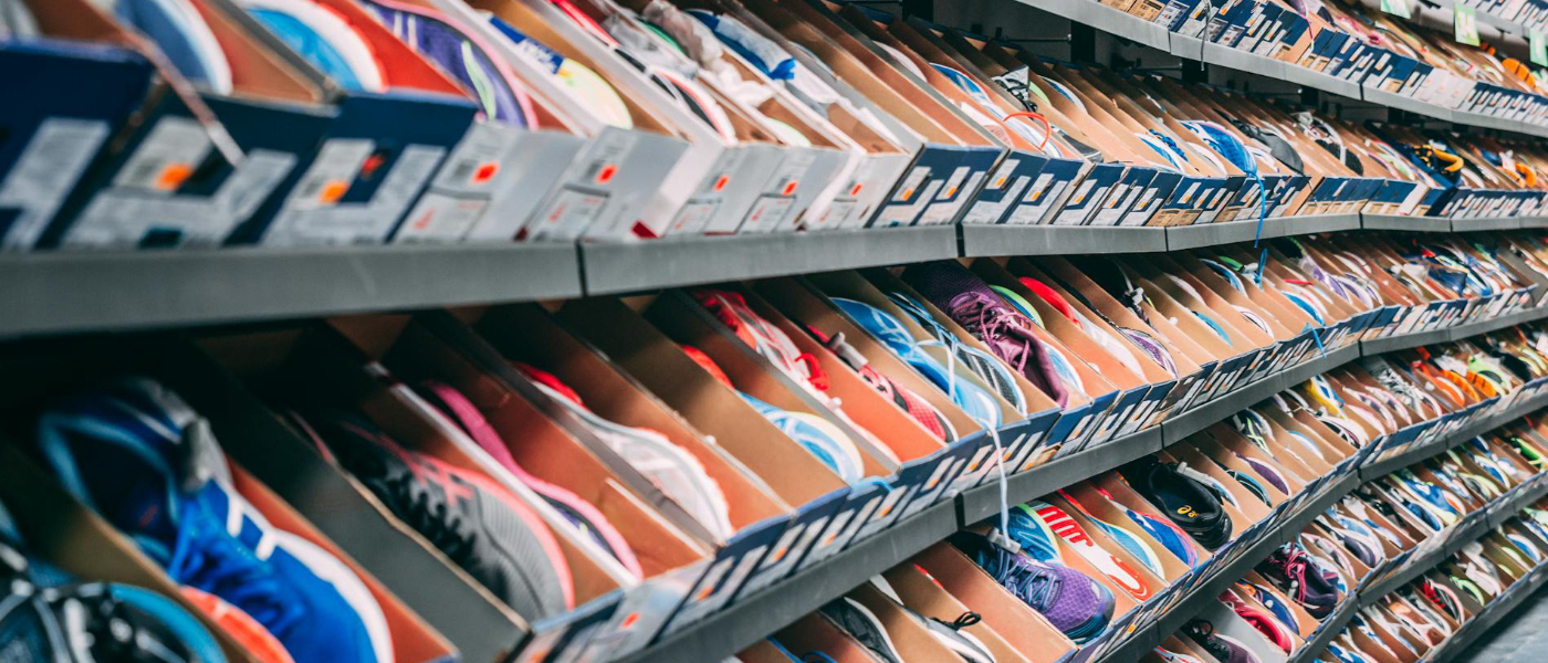 Regale mit zahlreichen Sneakern in offenen Kartons, dicht aneinandergereiht in einem Geschäft.