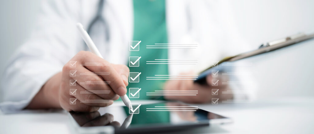 Eine digitale Grafik einer Checkliste mit abgehakten Kästchen schwebt über einem Tablet im Vordergrund. Ein Arzt im unscharfen Hintergrund, bekleidet mit weißem Kittel, grünem Kasack und Stethoskop, bearbeitet die Liste mit einem digitalen Eingabestift.
