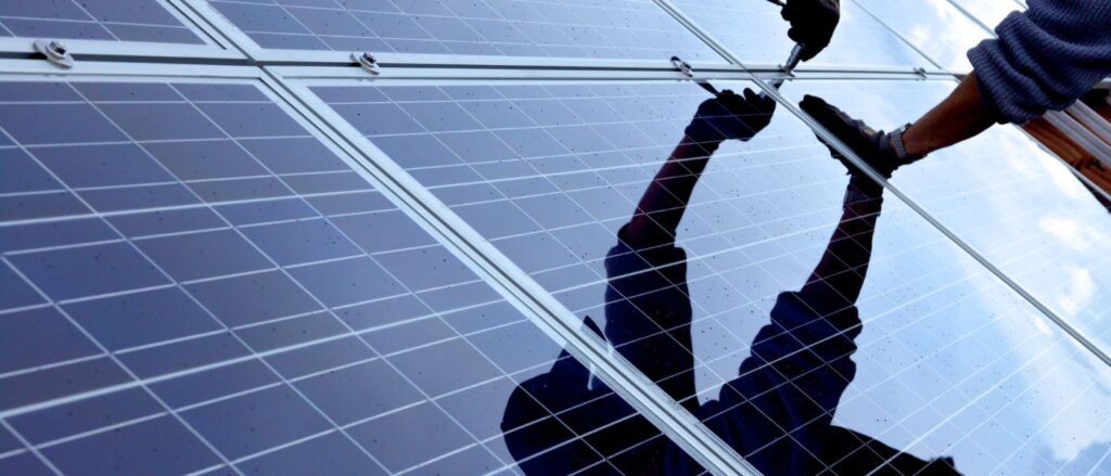 Person montiert Solaranlage mit Werkzeug in der Hand