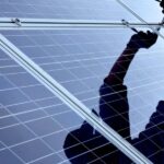 Person montiert Solaranlage mit Werkzeug in der Hand