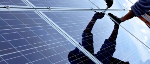 Person montiert Solaranlage mit Werkzeug in der Hand