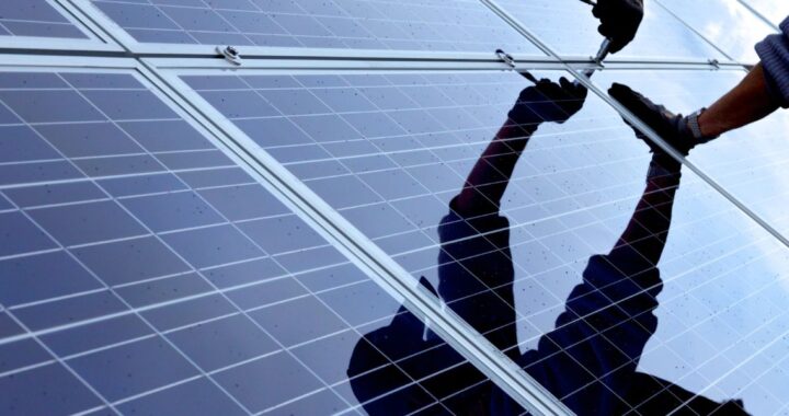 Person montiert Solaranlage mit Werkzeug in der Hand