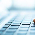 Finger drückt Taste auf Laptoptastatur