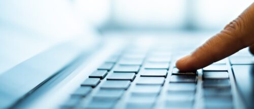 Finger drückt Taste auf Laptoptastatur