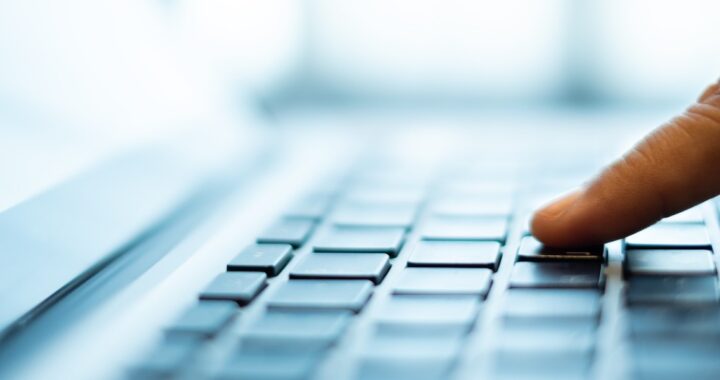 Finger drückt Taste auf Laptoptastatur