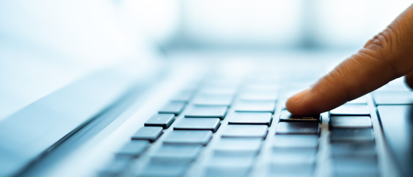 Finger drückt Taste auf Laptoptastatur